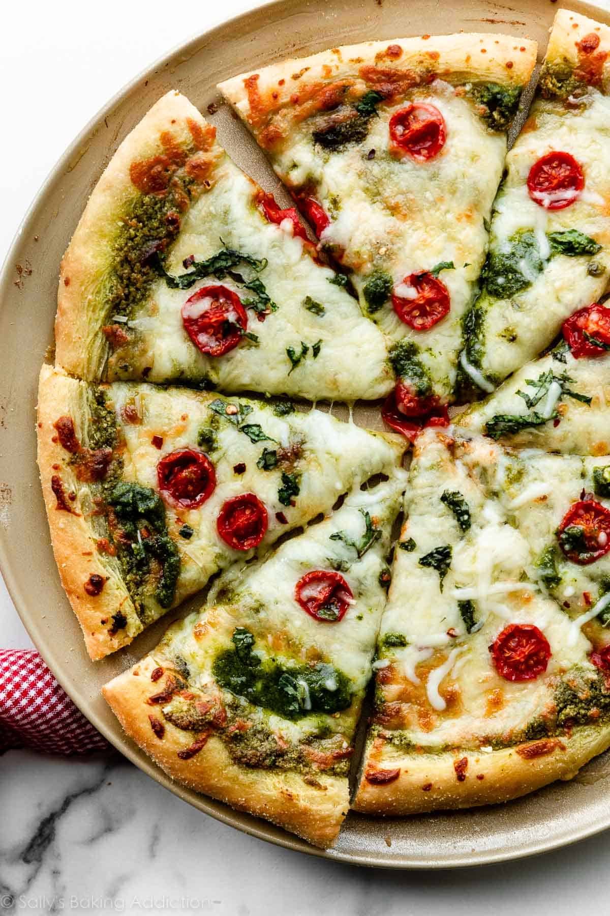 baked and sliced pesto pizza with mozzarella cheese and tomatoes.