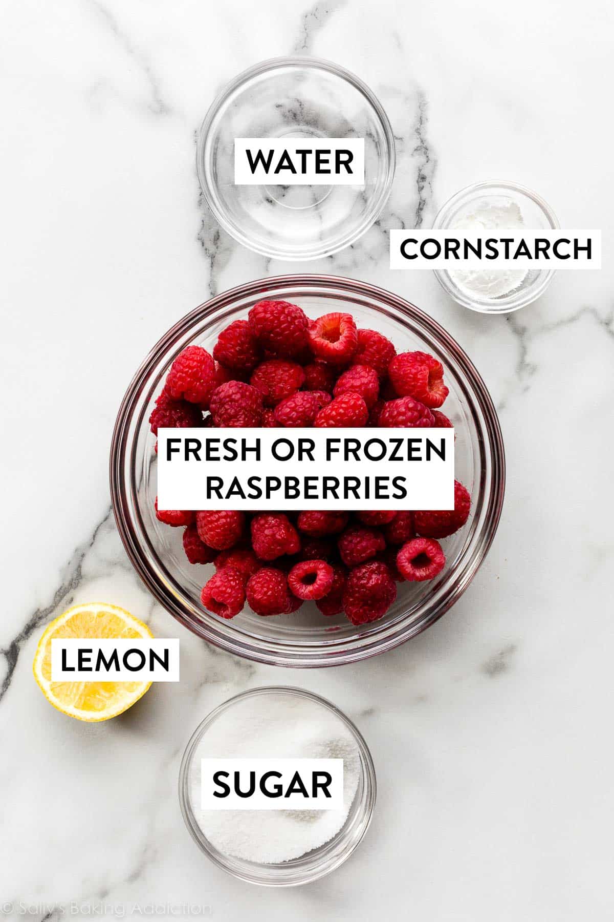 raspberries, lemon, sugar, cornstarch, and water in bowls on marble countertop.