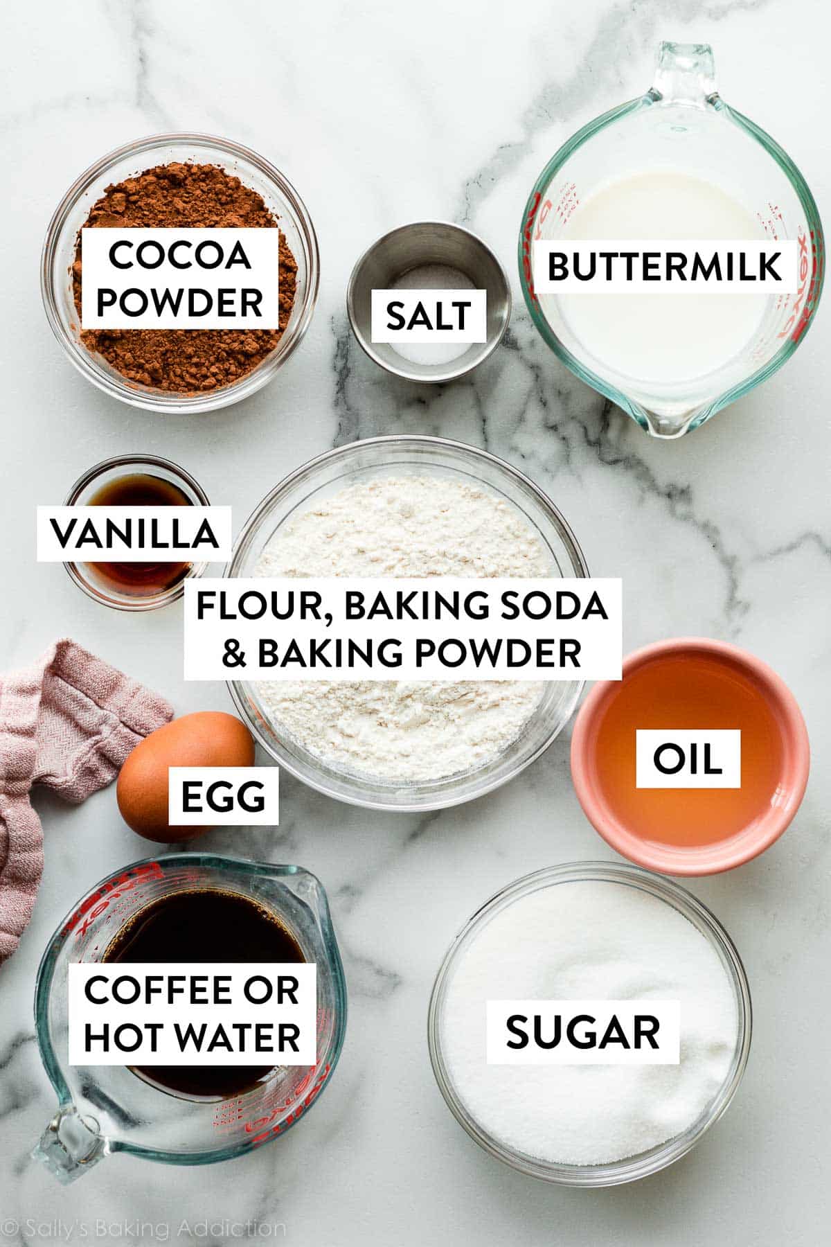 flour, baking soda, baking powder, oil, buttermilk, cocoa powder, coffee, and other ingredients on counter.