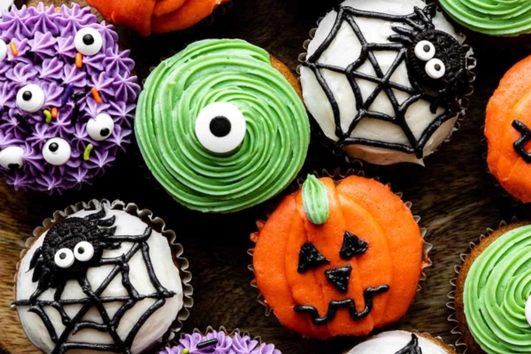 decorated Halloween cupcakes including purple monsters, green monsters, spiders and spider webs, and pumpkin Jack-O-Lanterns.