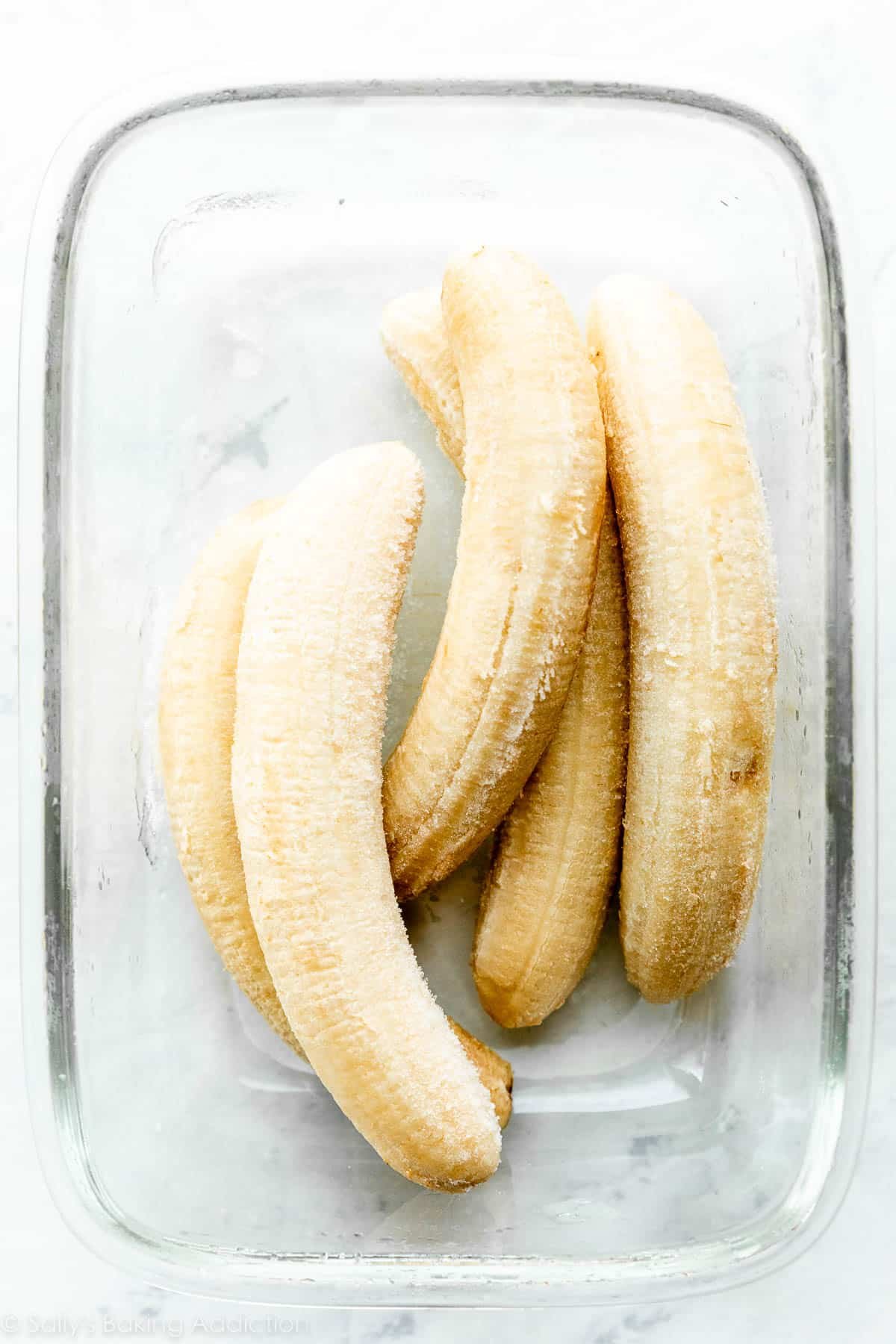 5 banane congelate in un contenitore rettangolare di vetro.