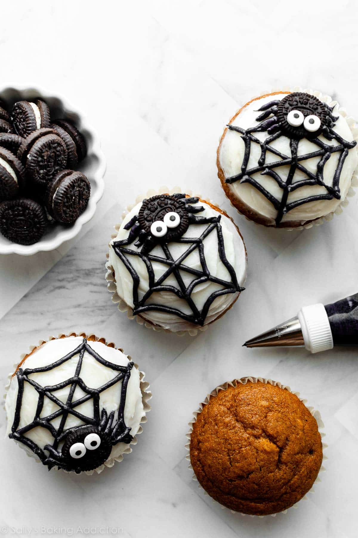3 spider and spider web decorated cupcakes with white and black frosting.