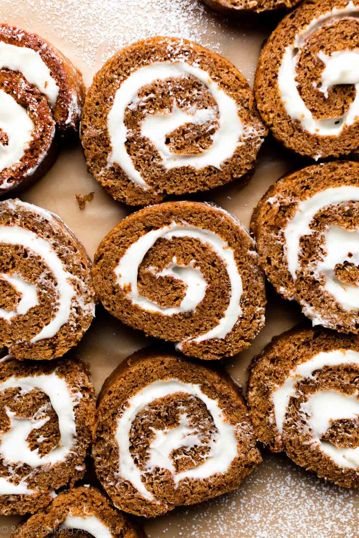 slices of pumpkin roll filled with cream cheese frosting arranged on brown parchment paper sheet.