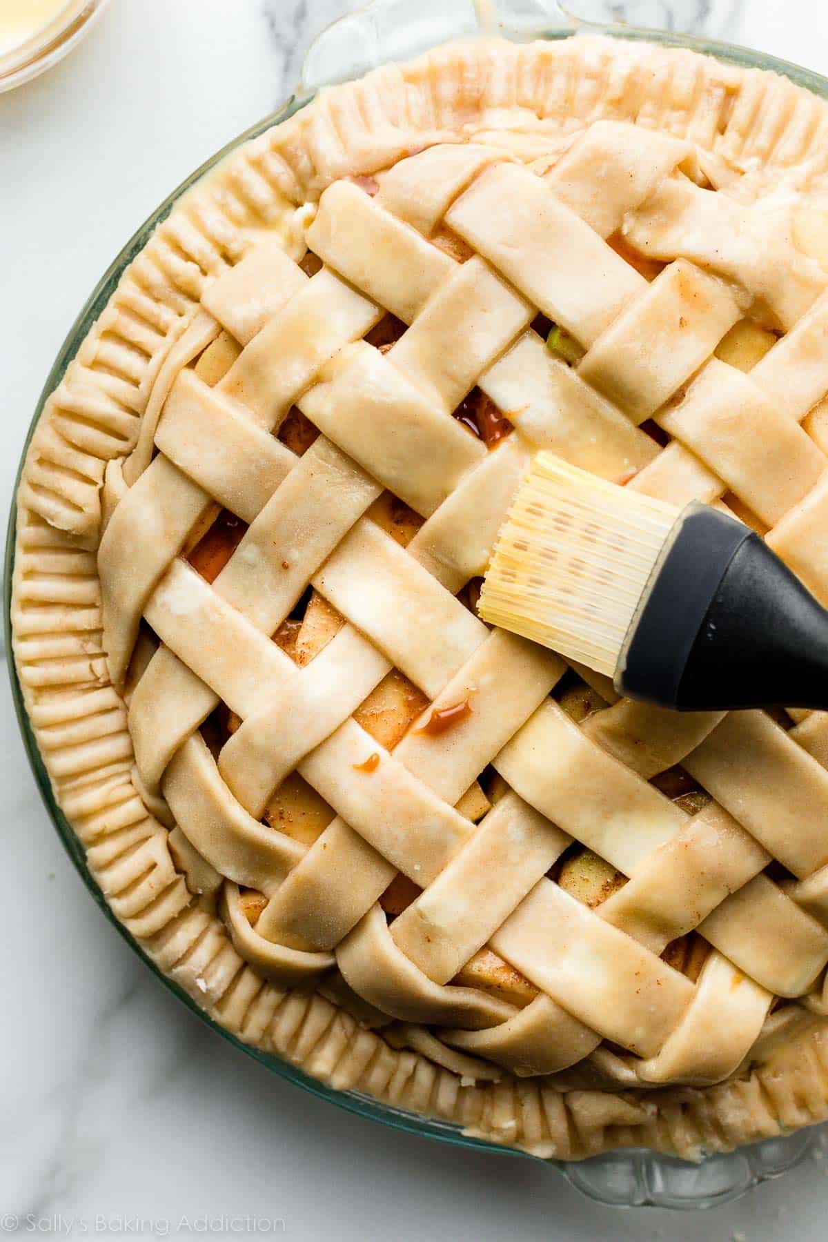 brushing egg wash on lattice top pie crust with silicone pastry brush.
