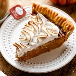 slice of chai spice pumpkin pie on white plate with toasted meringue topping.