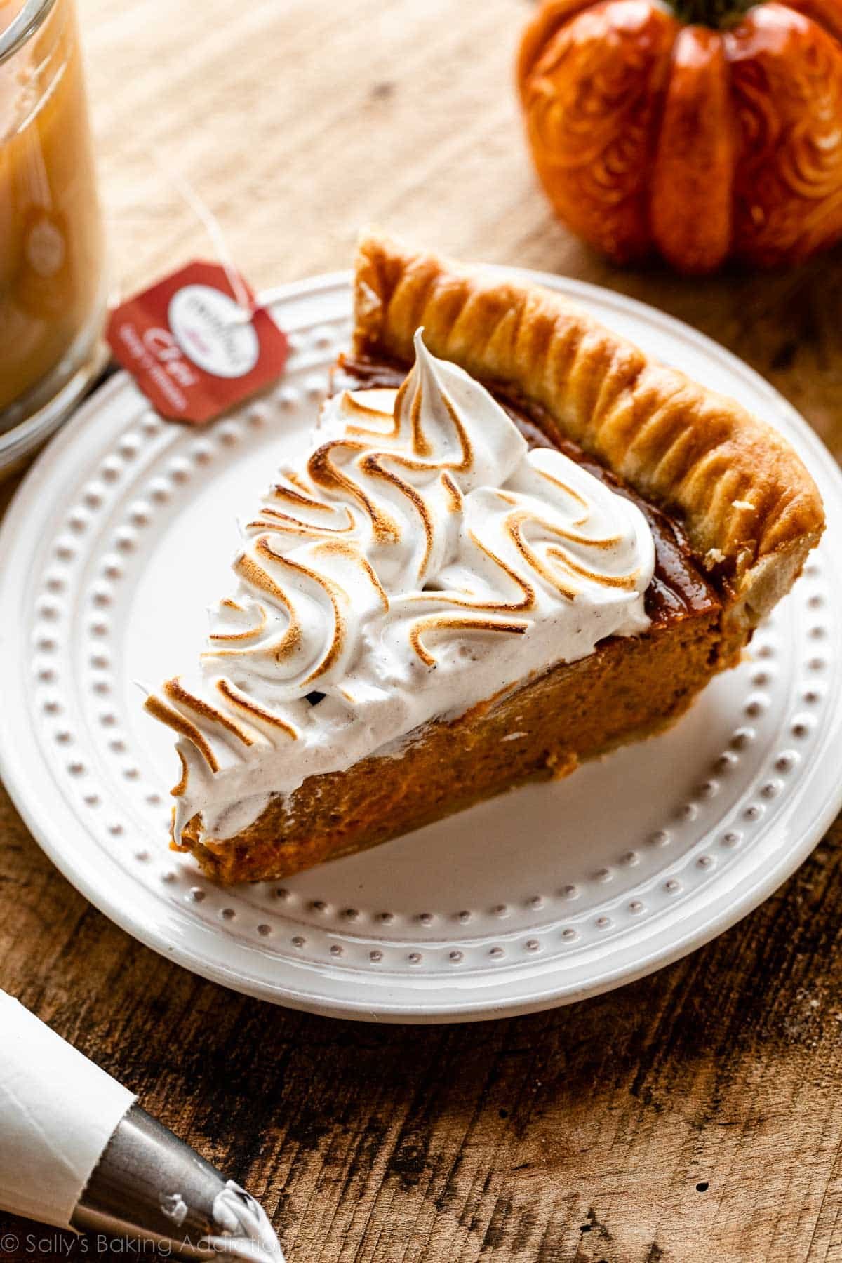 slice of chai spice pumpkin pie on white plate with toasted meringue topping.