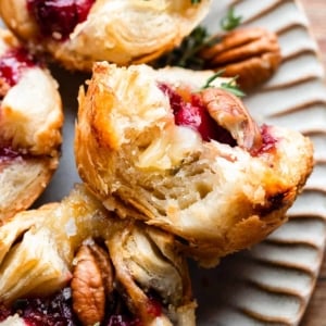 cranberry sauce and brie in a flaky puff pastry tart shown with a bite taken out.