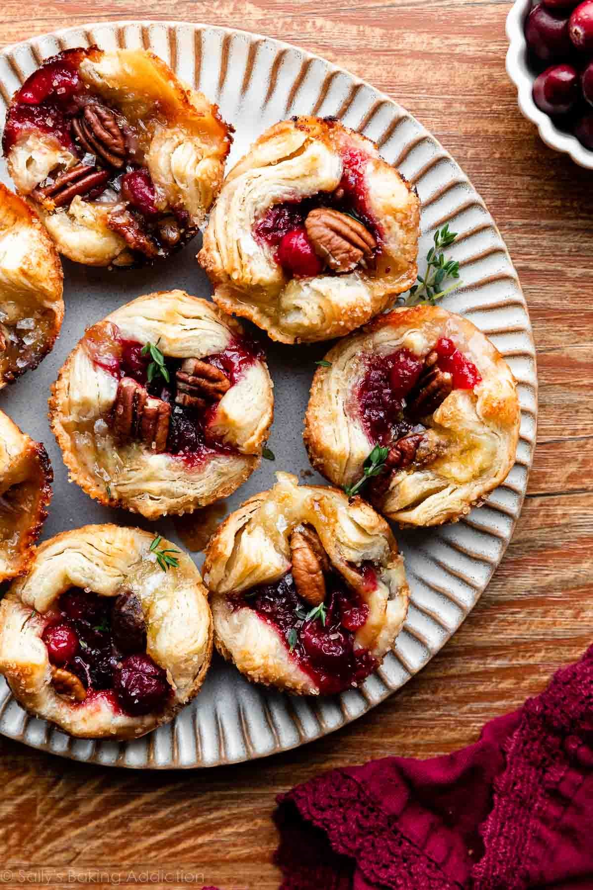 cranberry pecan and brie cheese puff pastry bites on gray plate on wooden backdrop.