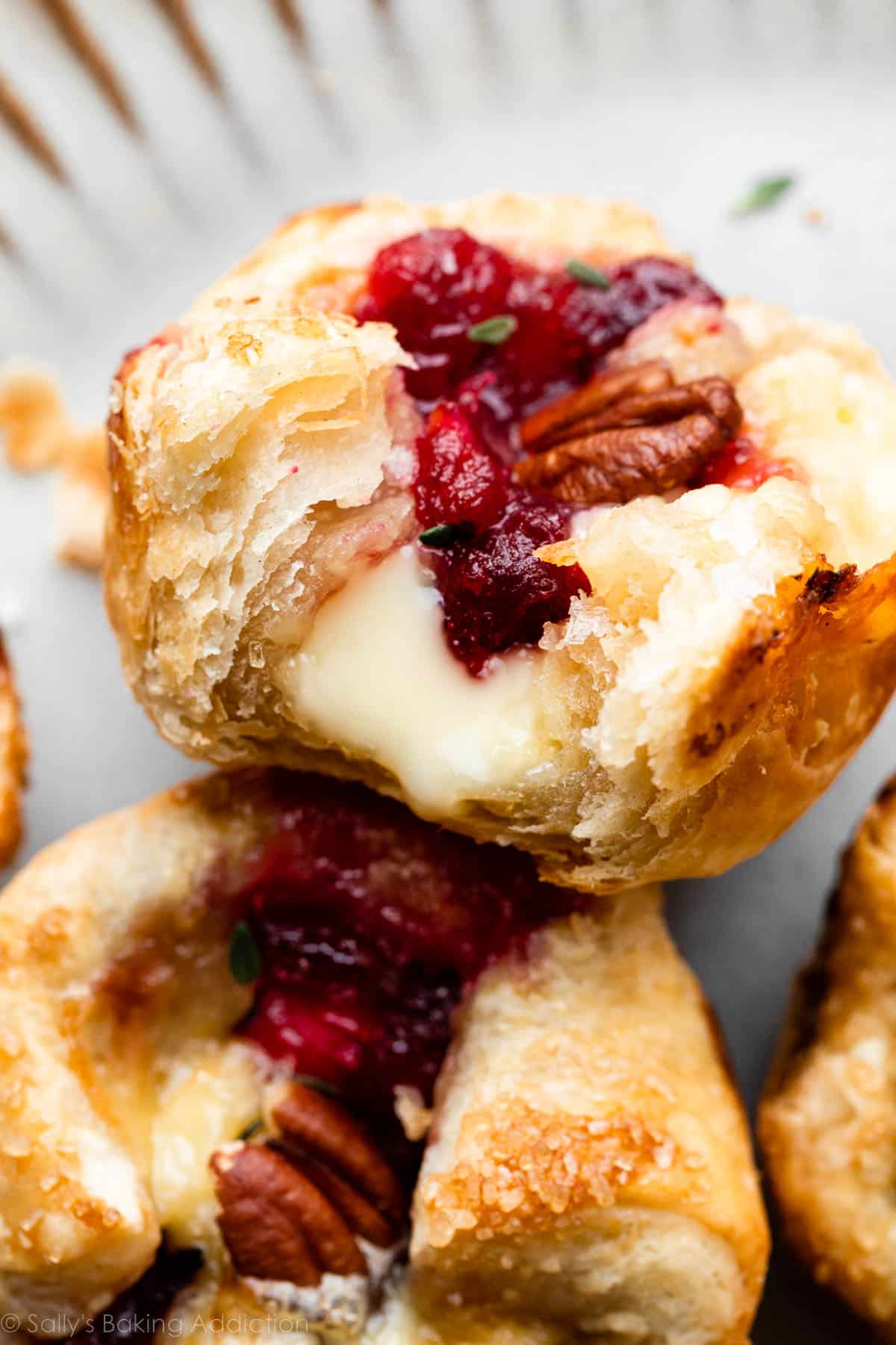 cranberry sauce and brie in a flaky puff pastry tart shown with a bite taken out.