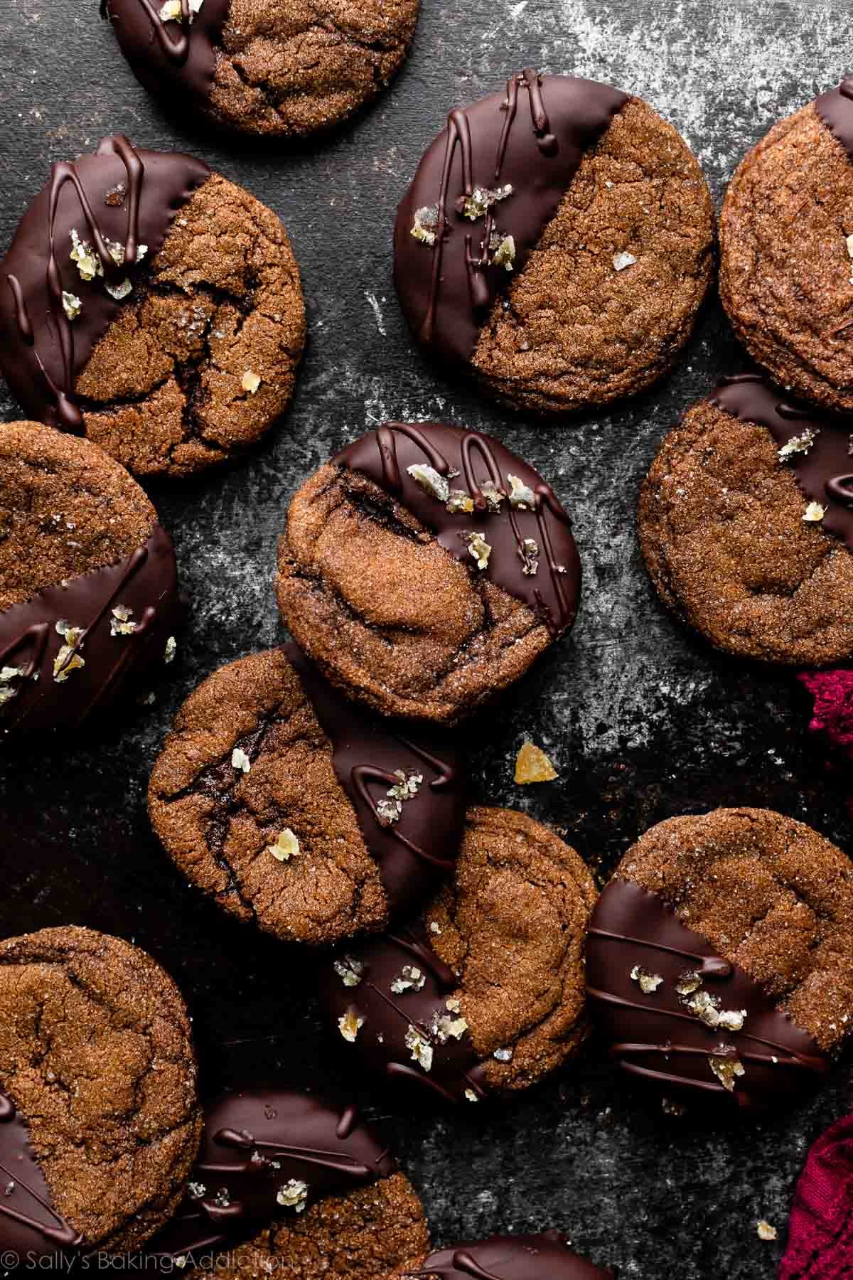 biscotti allo zenzero al cioccolato immersi nel cioccolato fondente e disposti su una tavola nera e grigia.