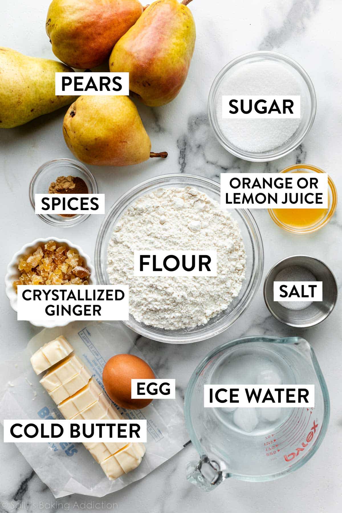 ingredienti sul bancone tra cui farina, pere, zucchero, sale, acqua ghiacciata, burro freddo, zenzero e altro ancora.
