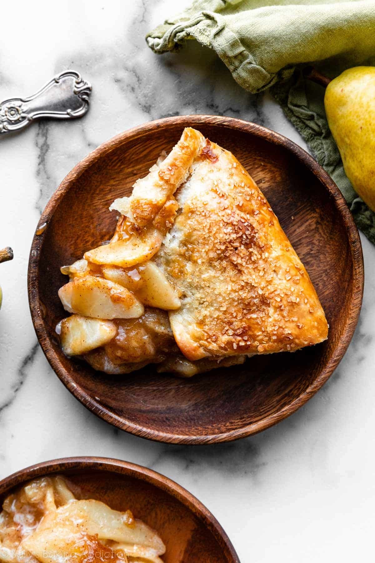 slice of ginger pear galette with golden brown crust on brown wood plate.
