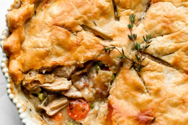 turkey pot pie with 1 slice removed to show carrots, peas, turkey, and gravy filling.