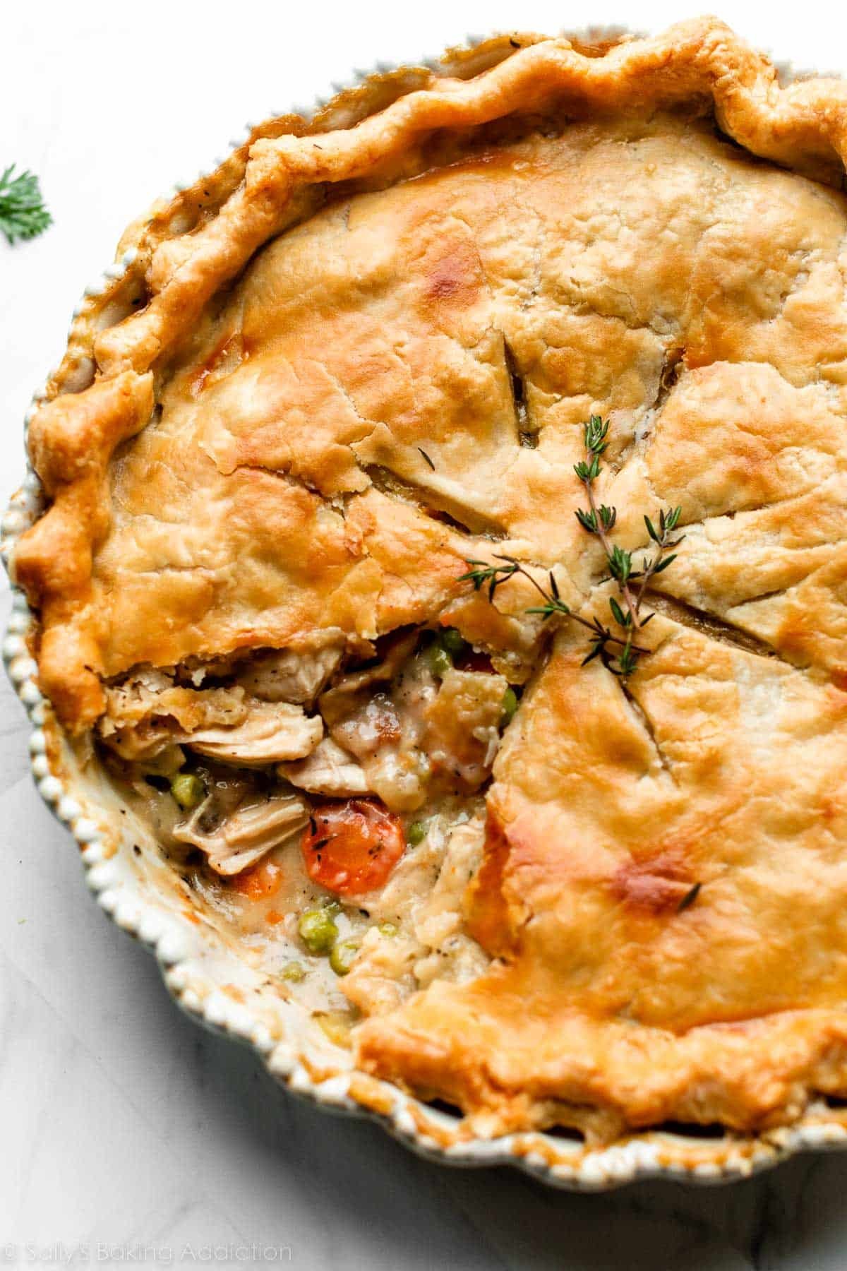turkey pot pie with 1 slice removed to show carrots, peas, turkey, and gravy filling.