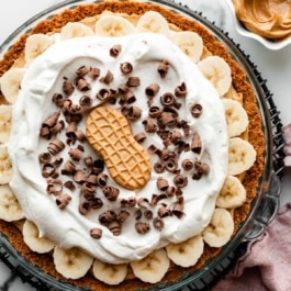 peanut butter banana cream pie with whipped cream, chocolate curls, and Nutter Butter cookie on top.