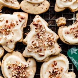 pecan sugar cookies with icing and crushed pecans on top in the shape of mittens and Christmas tree.