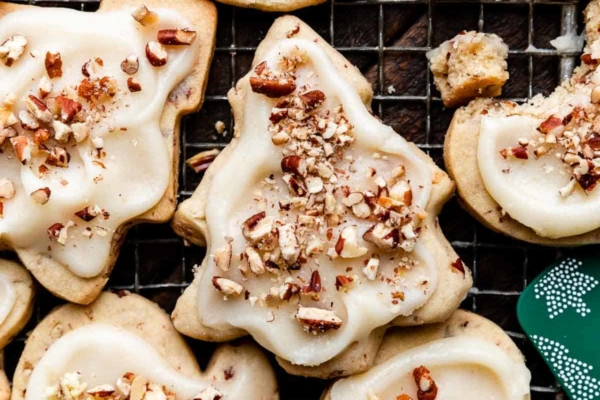 pecan sugar cookies with icing and crushed pecans on top in the shape of mittens and Christmas tree.