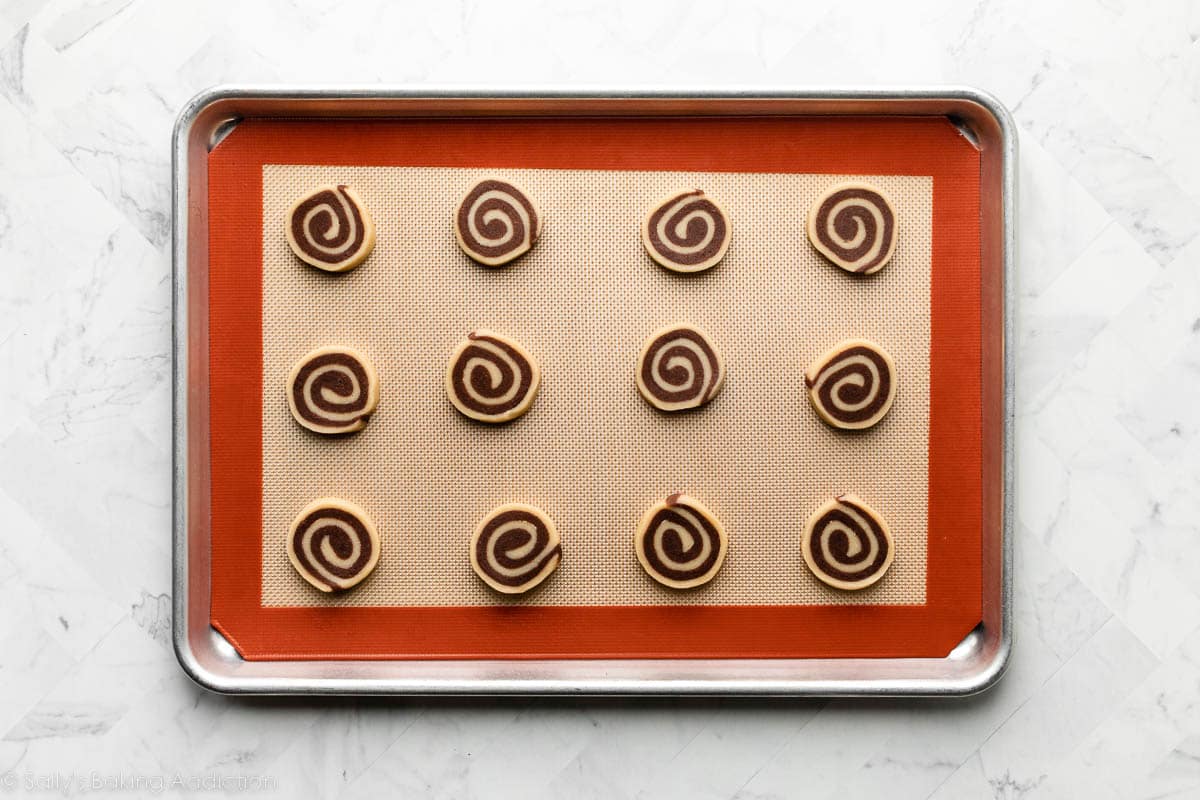 sliced pinwheel cookies on lined baking sheet before baking.