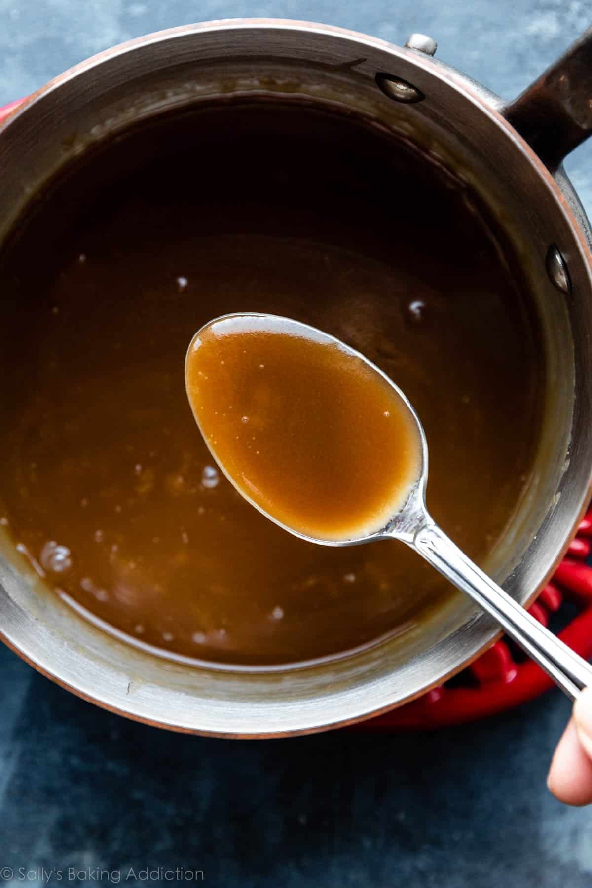 spoonful of caramel sauce over a pot of caramel.