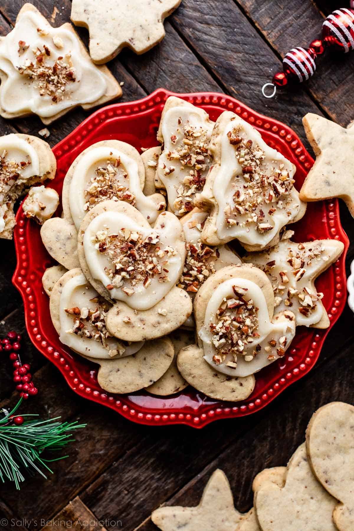 red plate of pecan sugar cookies with brown butter icing and crushed toasted pecans on top.