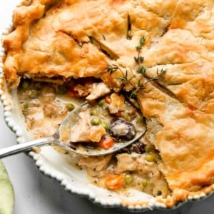 turkey pot pie with slices removed to show carrots, peas, mushrooms, turkey, and gravy filling.