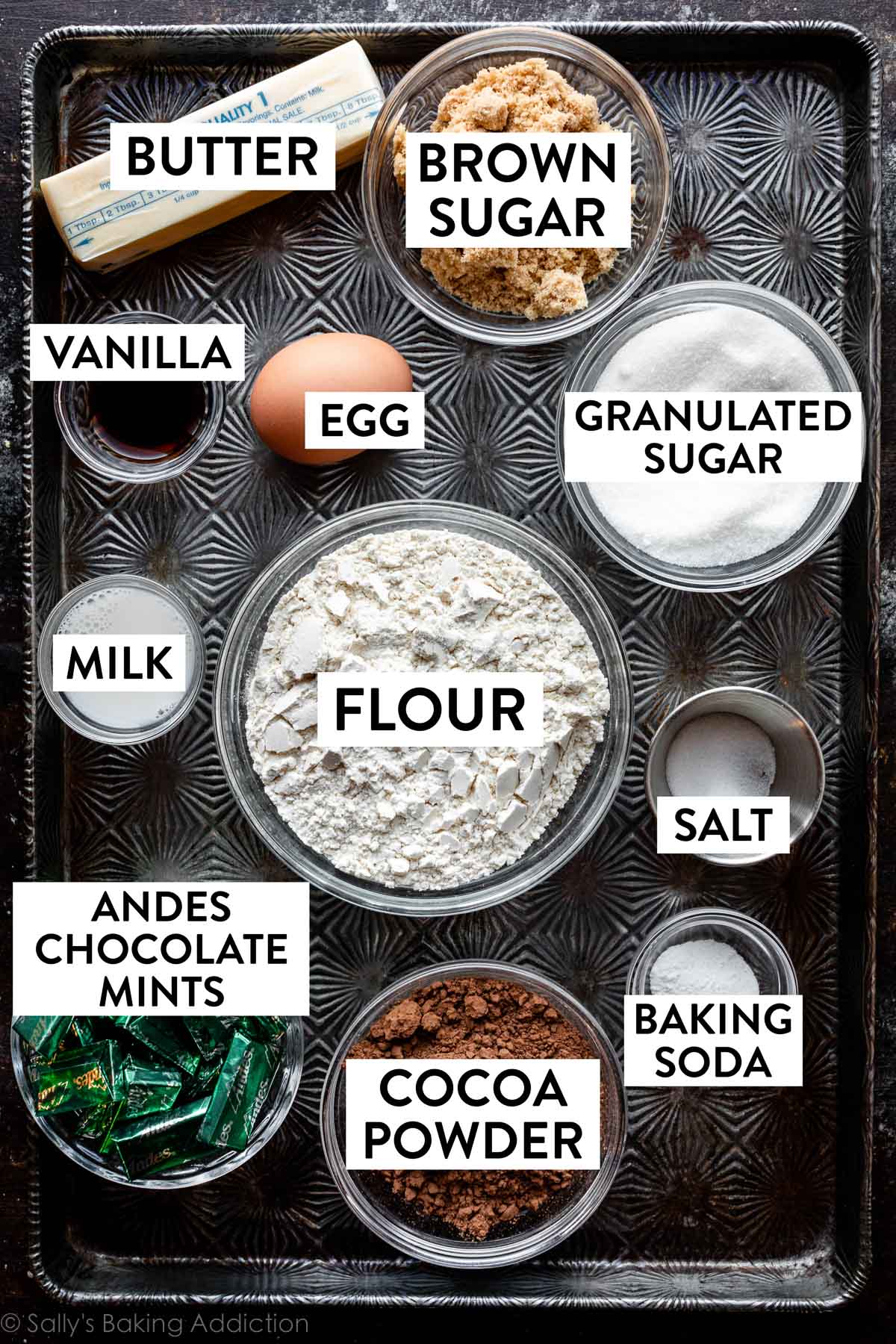 ingredients on baking tray including flour, cocoa powder, butter, egg, brown sugar, bowl of Andes mints, and more.