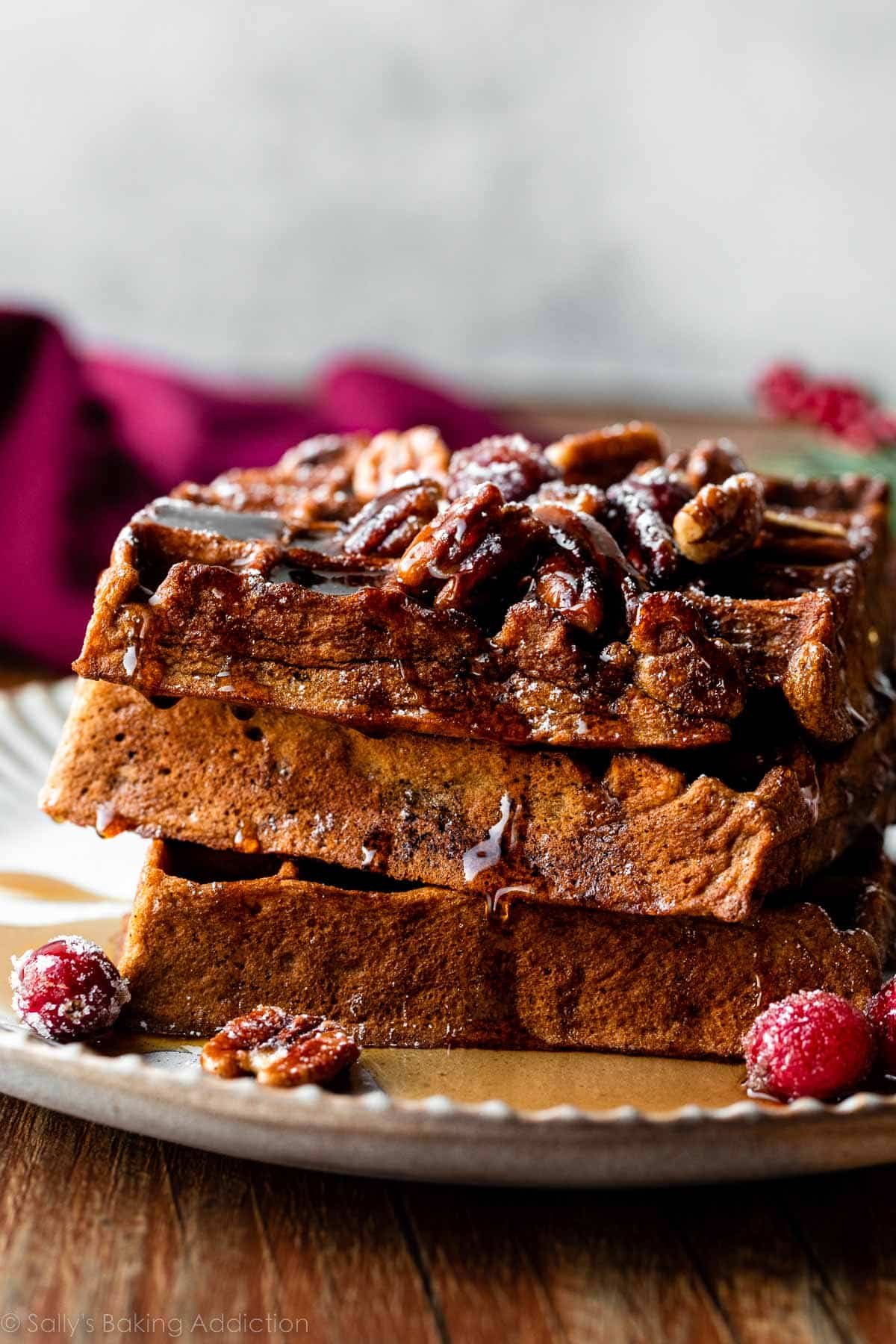 stack of 3 gingerbread waffles with pecans on top.