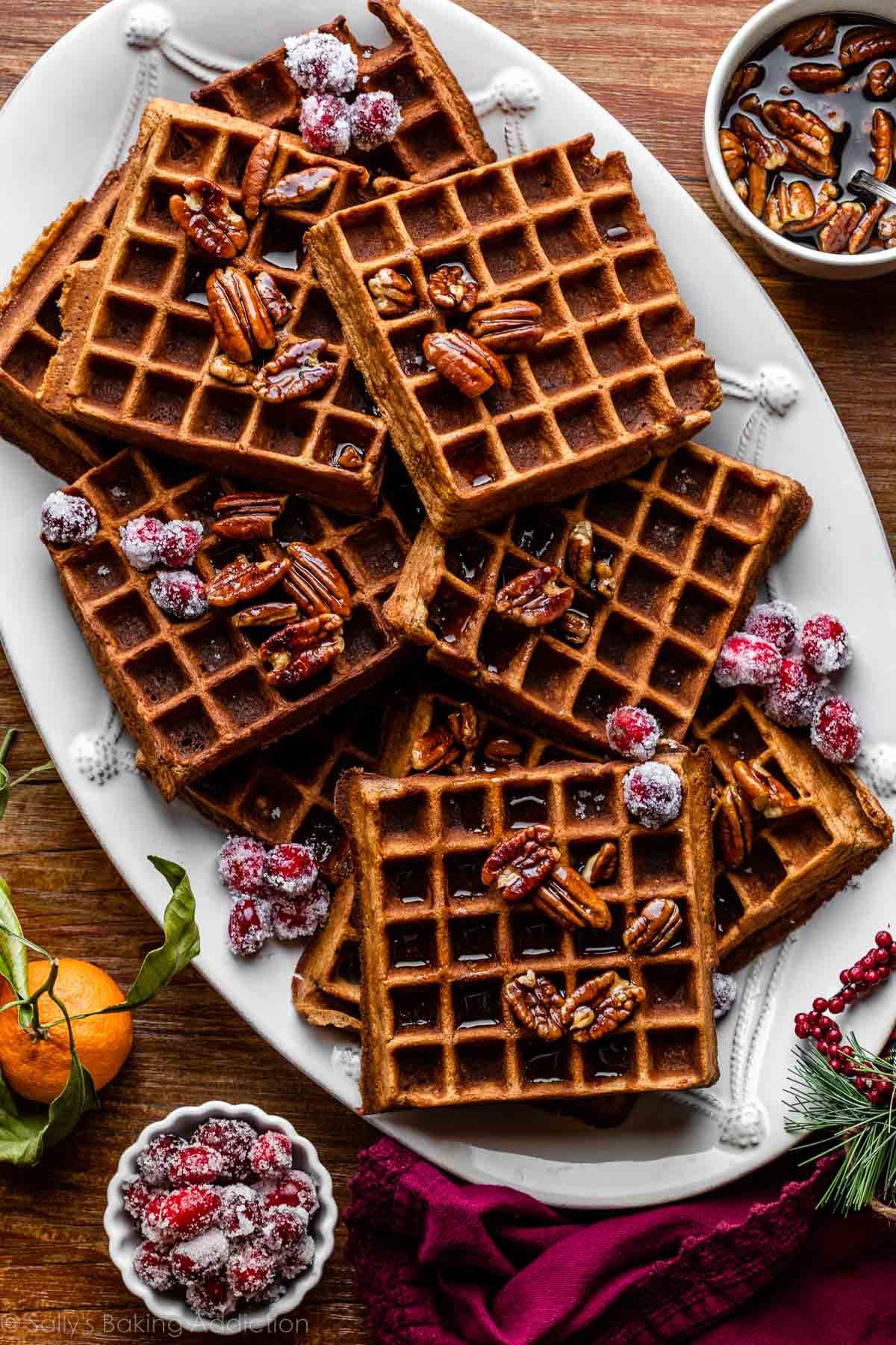 serving platter of gingerbread waffles with sugared cranberries and pecans.