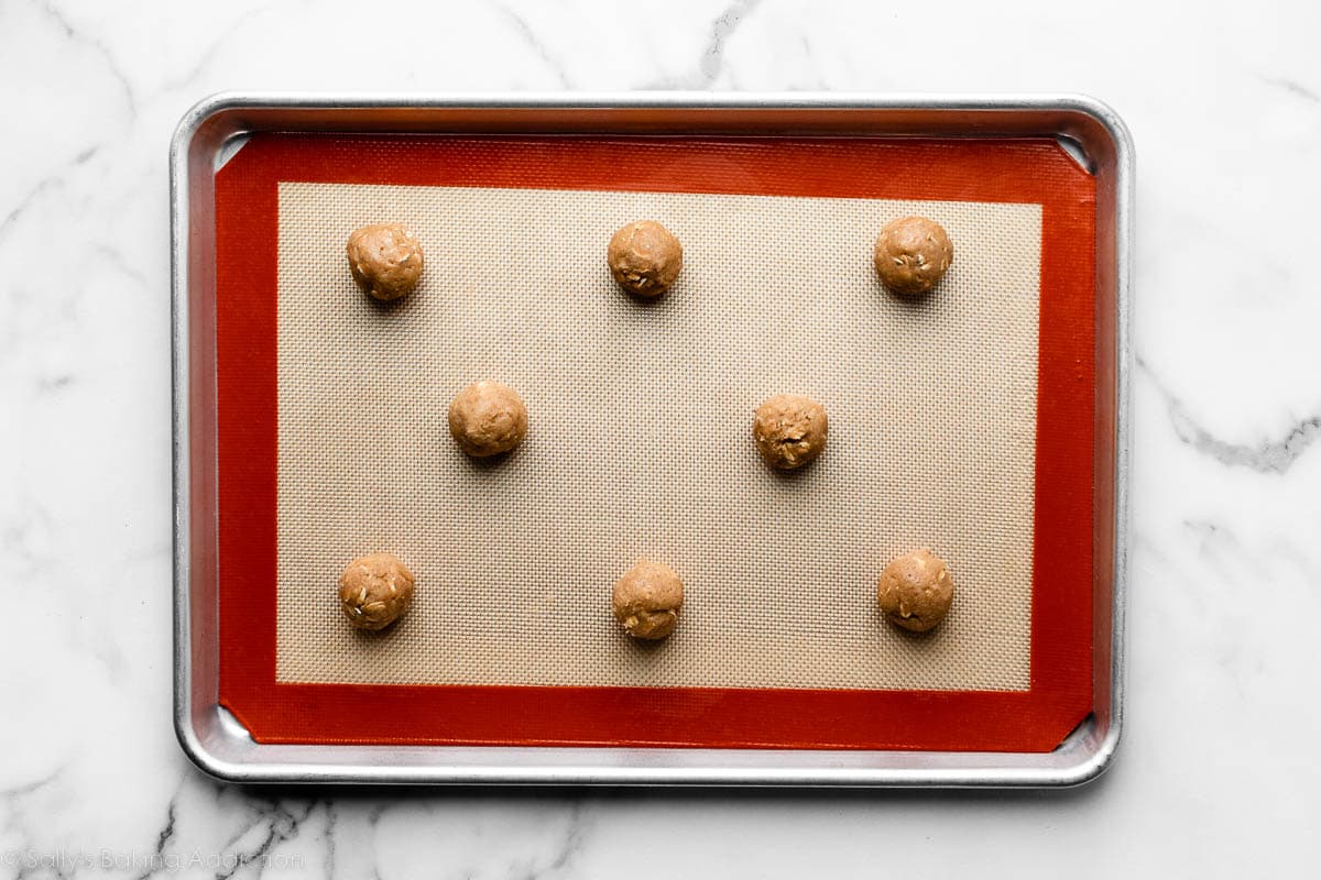 oatmeal cookie dough balls arranged on Silpat-lined baking sheet.