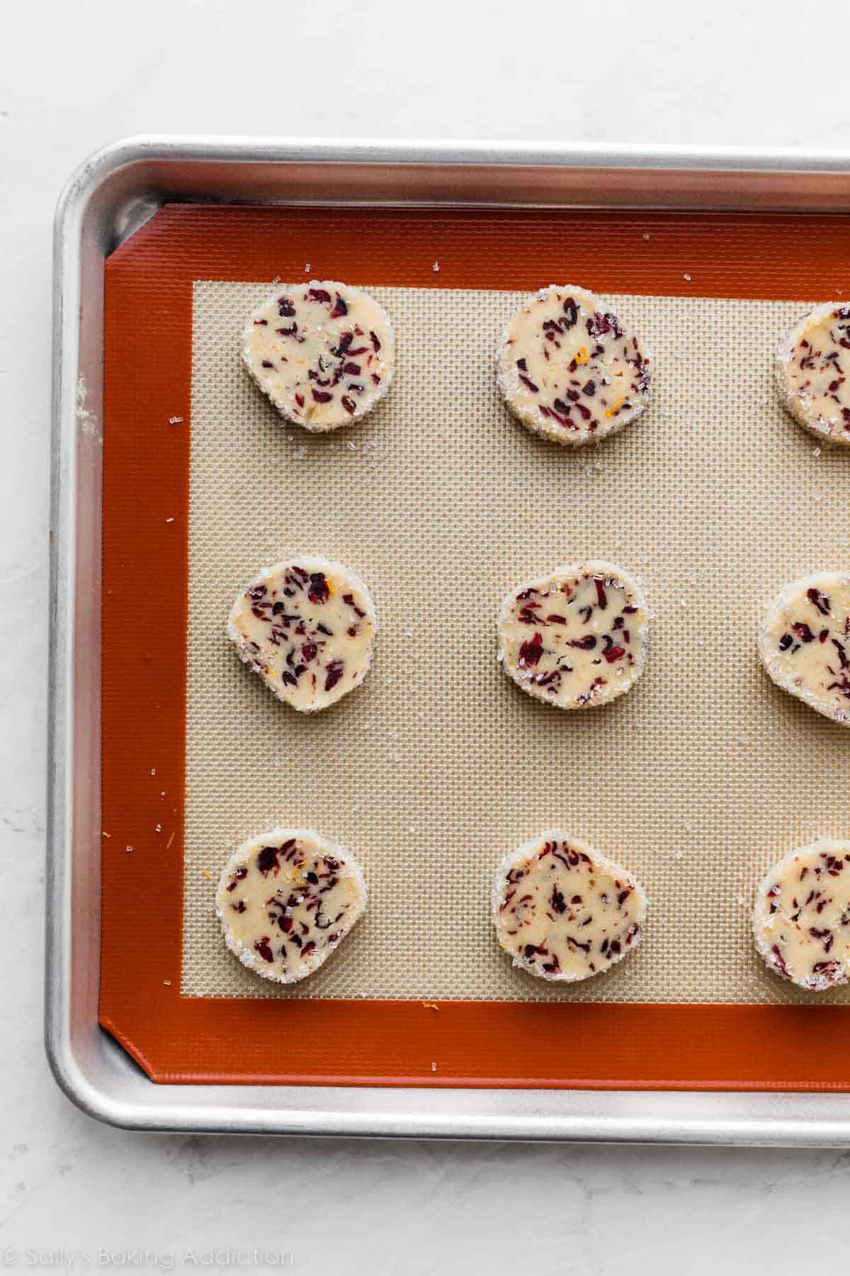 sliced cranberry cookies arranged on Silpat-lined baking sheet.