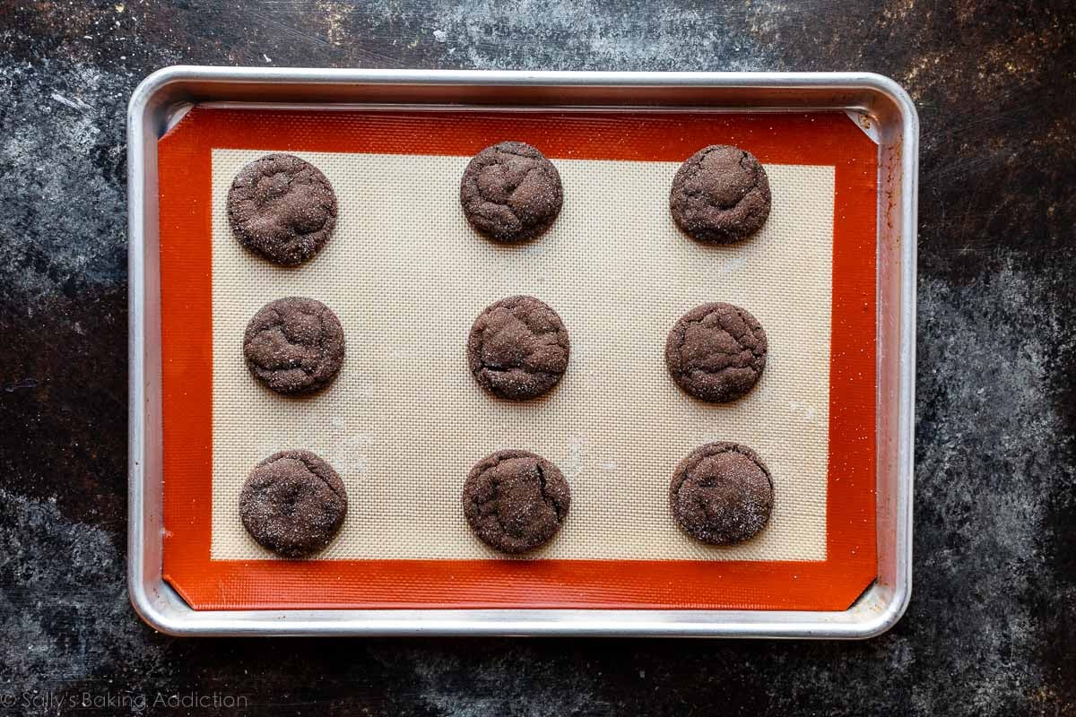 Silpat-lined baking sheet with 9 chocolate cookies arranged on top.