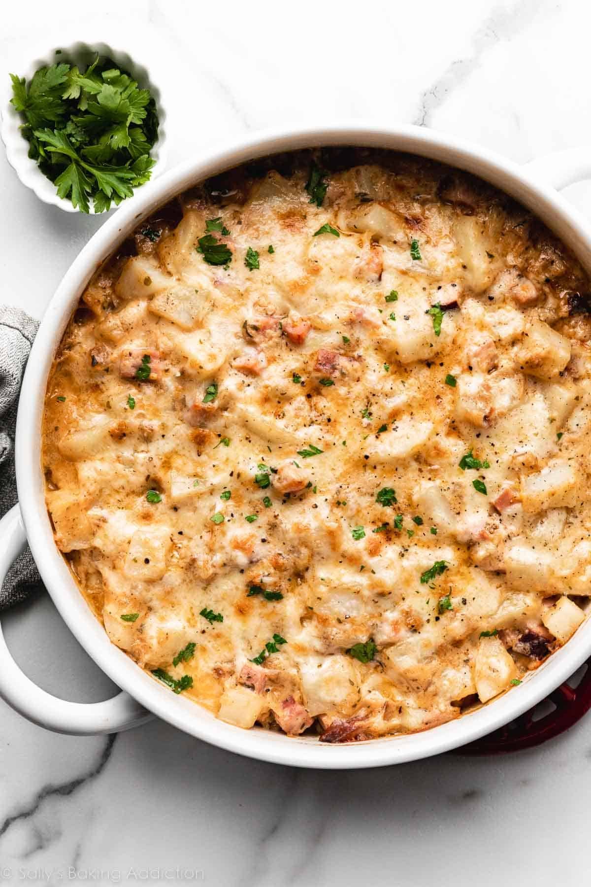 potato casserole with ham and melted cheese with fresh parsley sprinkled on top.