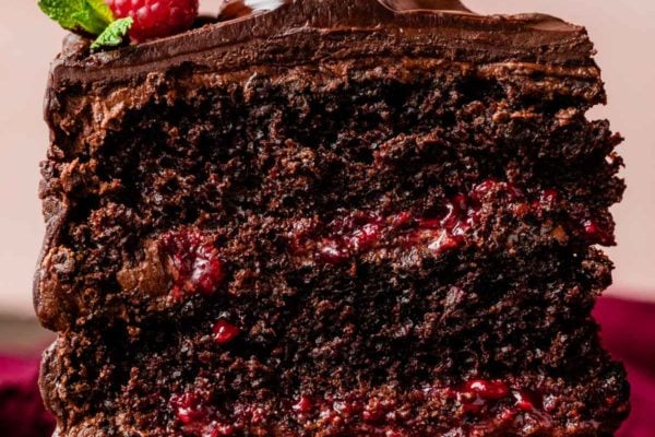 slice of 3-layer chocolate raspberry cake with chocolate raspberry ganache and raspberry filling.