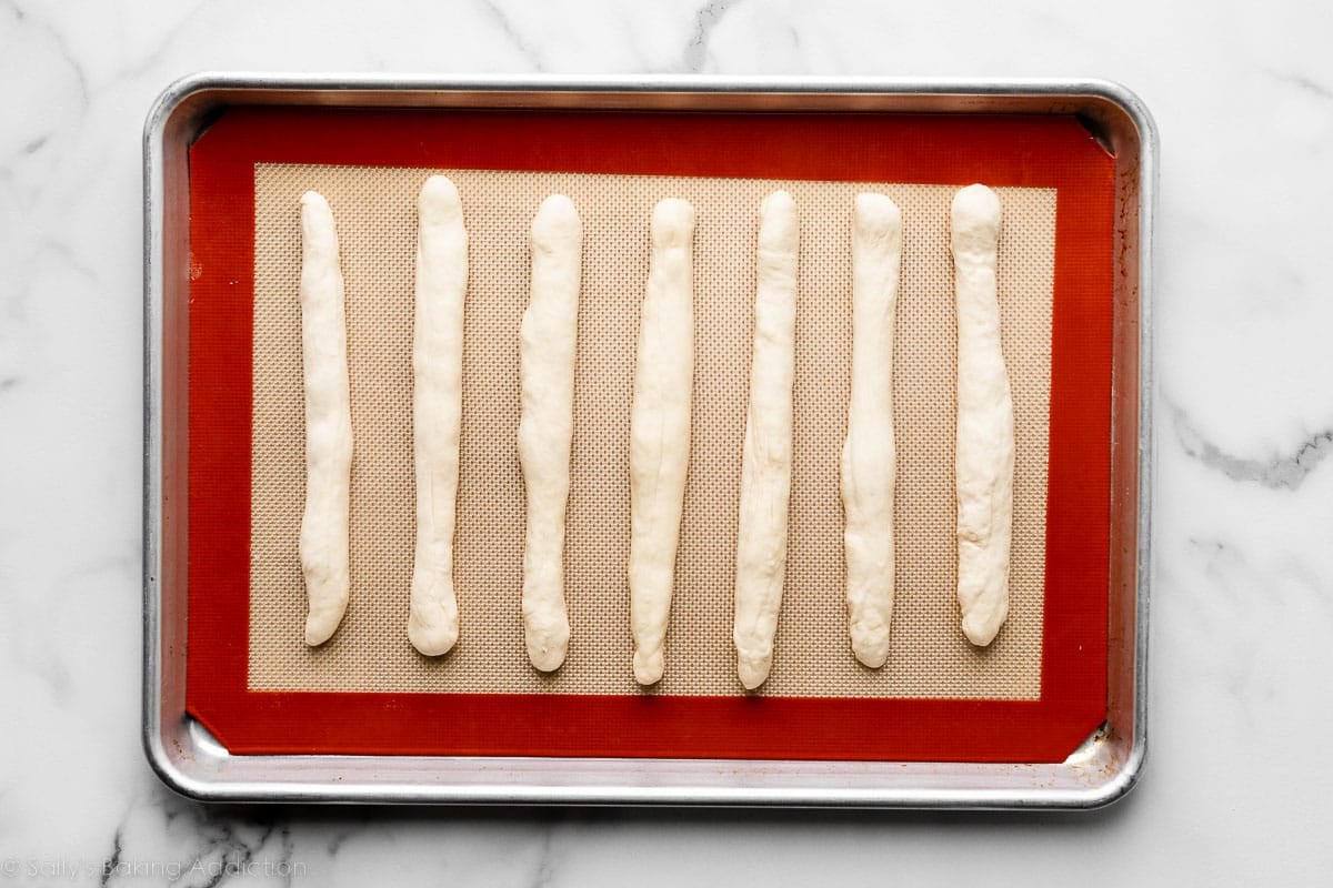 7 shaped breadsticks before baking on silicone baking mat-lined baking sheet.
