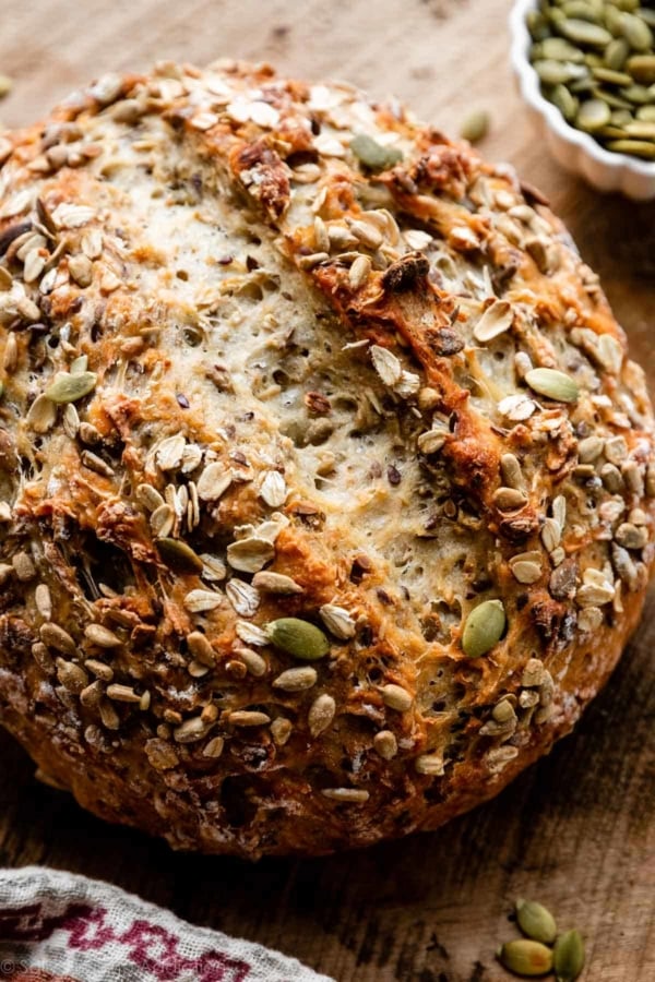 round boule of seeded bread on wooden cutting board.