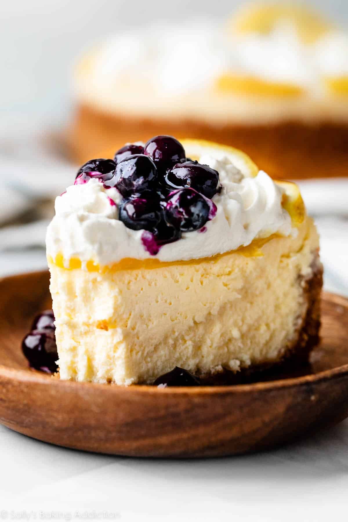 lemon cheesecake with whipped cream and blueberry sauce on top