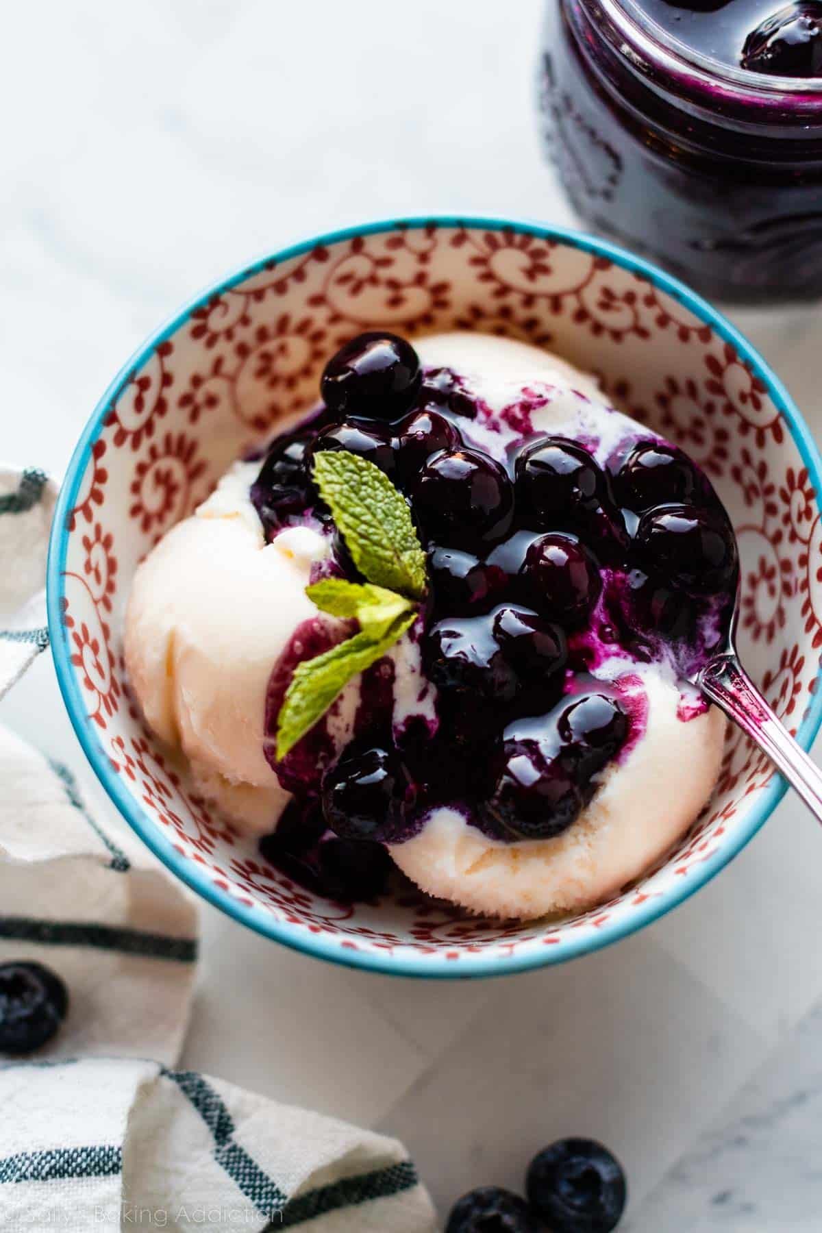 blueberry sauce topping spooned over bowl of vanilla ice cream.
