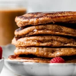 stack of whole wheat pancakes with maple syrup dripping down.