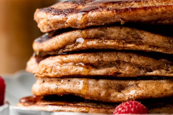 stack of whole wheat pancakes with maple syrup dripping down.