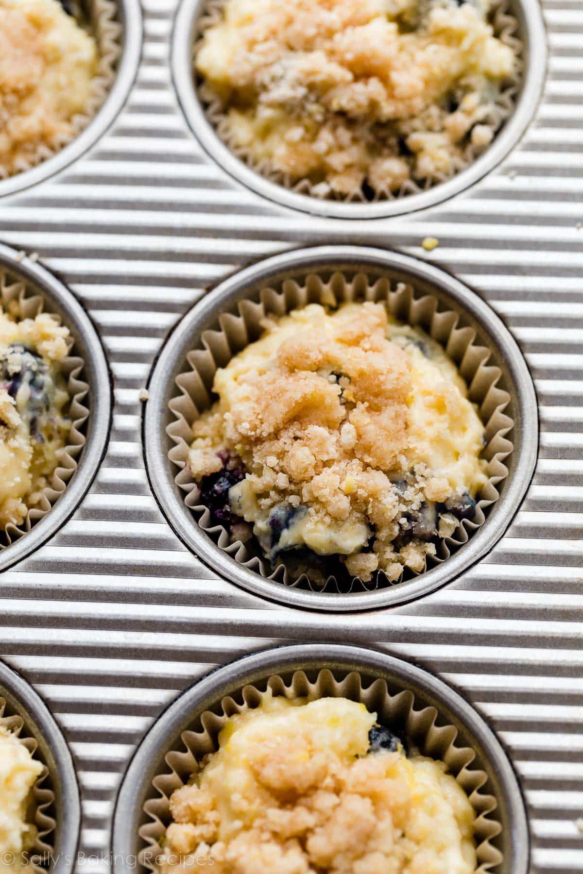 muffin batter with a crumb topping on top before baking in a muffin pan.