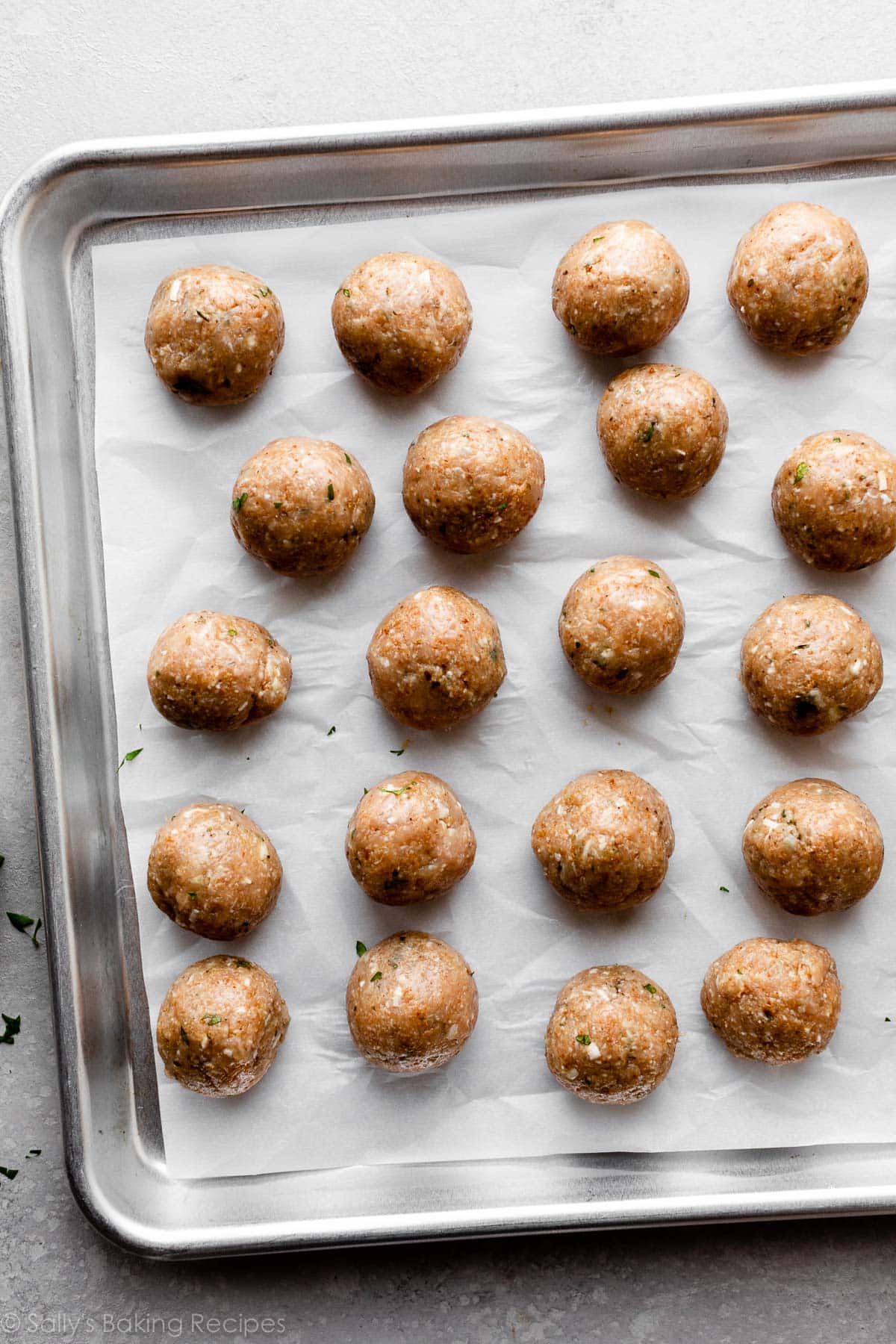 unbaked meatballs on parchment paper-lined baking sheet.