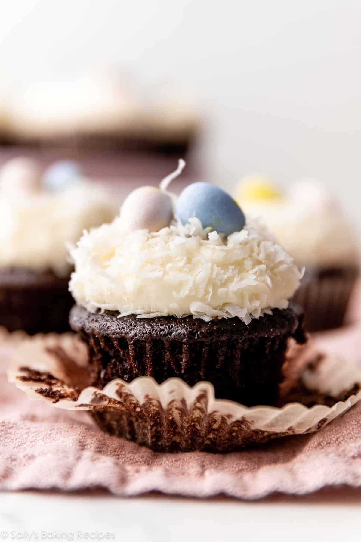 Easter chocolate cupcake with cream cheese frosting, coconut, and Easter egg candies on top.