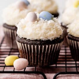 chocolate coconut Easter cupcakes on cooling rack with coconut and Easter egg candies topping.