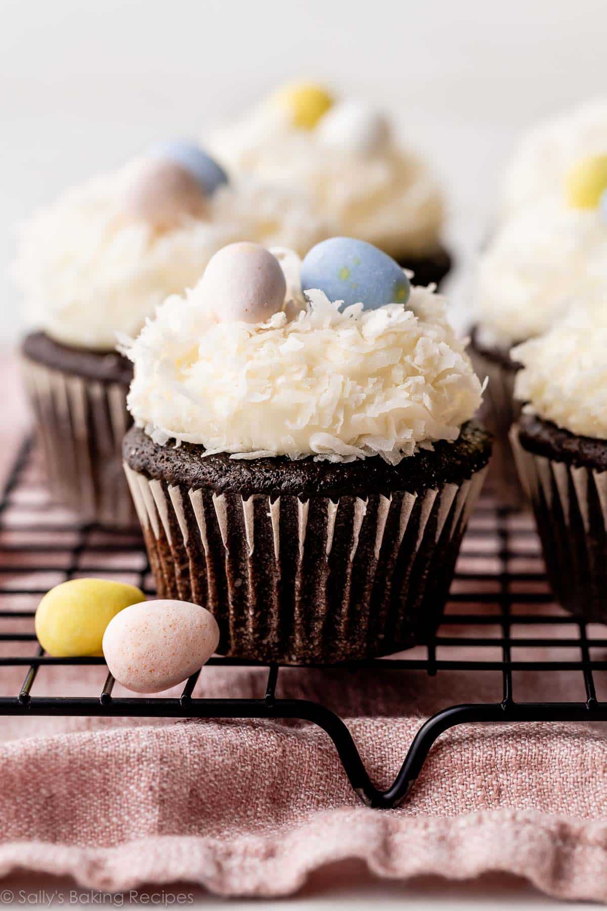 chocolate coconut Easter cupcakes on cooling rack with coconut and Easter egg candies topping.
