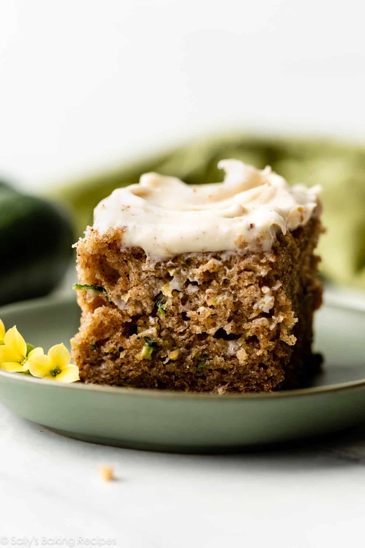 zucchini cake with brown butter cream cheese frosting on green plate.