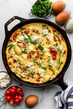 Mediterranean-inspired spinach and tomato frittata in cast iron skillet.