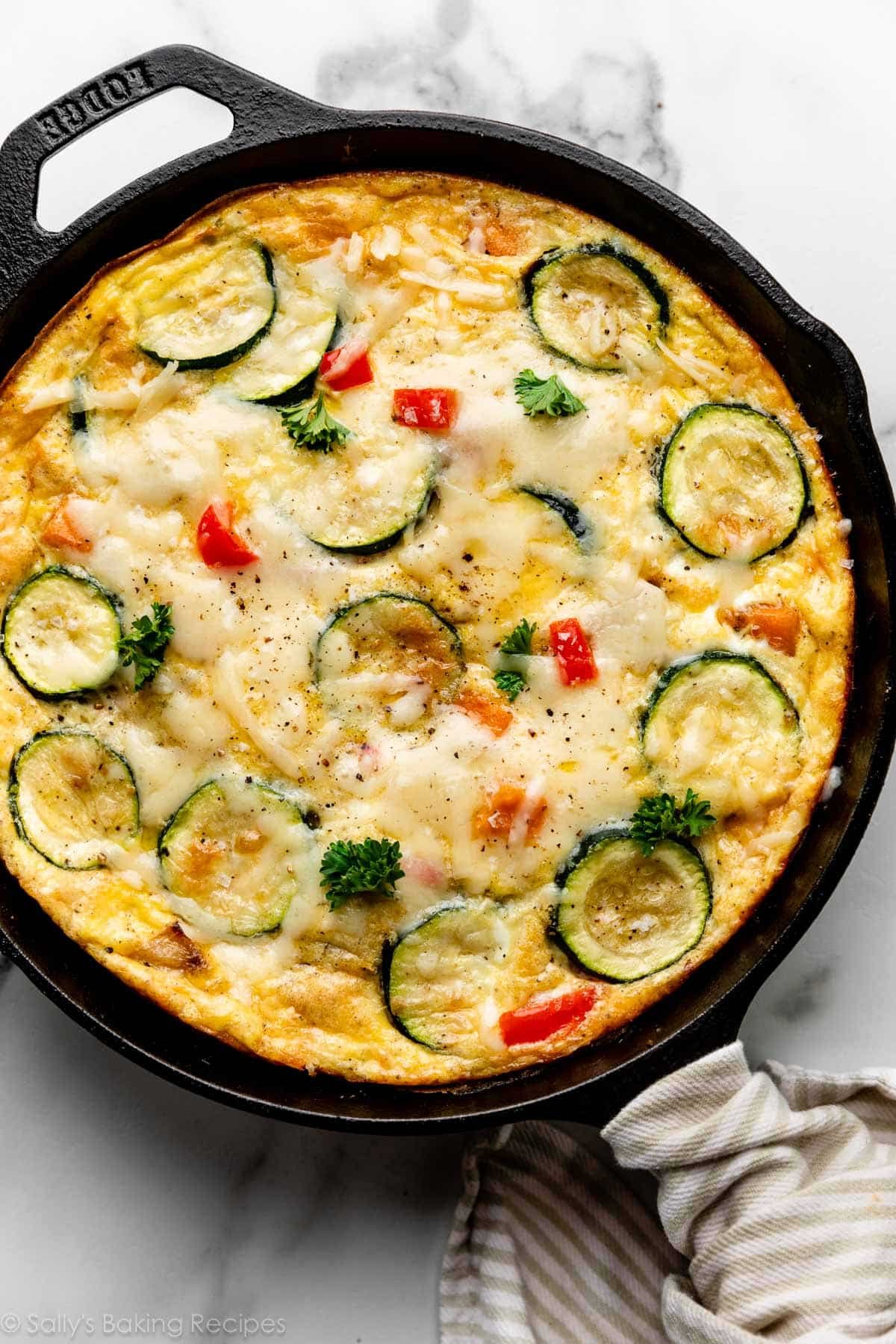 vegetable frittata with zucchini and red bell peppers in a cast iron skillet.