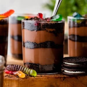 cups of dirt and worms pudding dessert with layers of crushed Oreo cookies, homemade chocolate pudding, and gummy worms on top.
