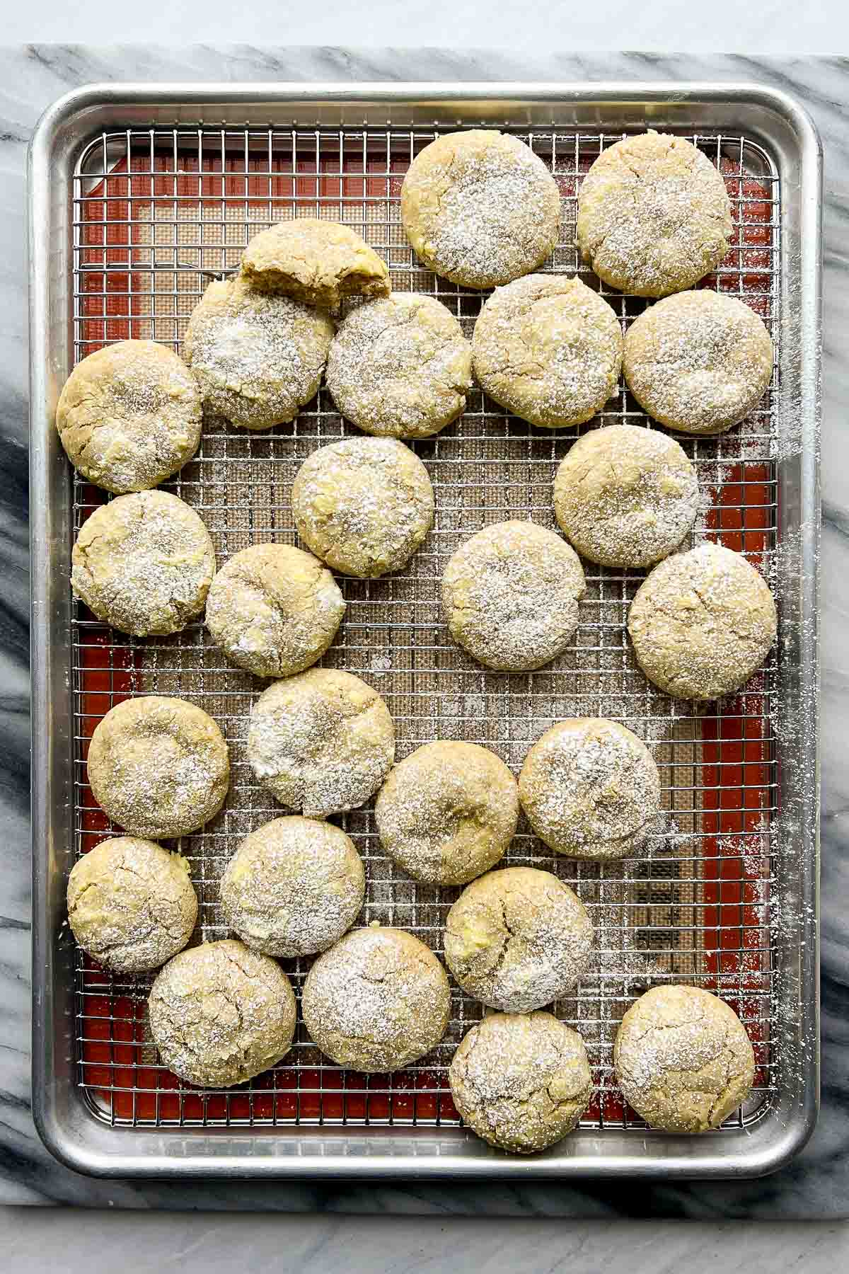 green cookies with confectioners' sugar on top on cooling rack on top of baking sheet.