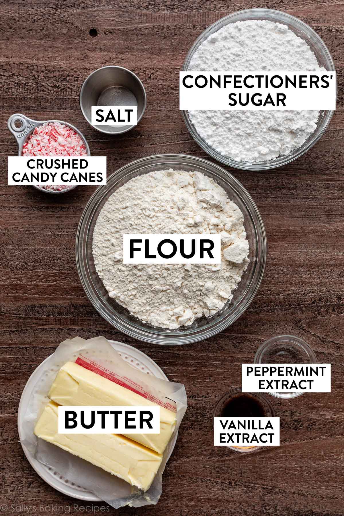 ingredients on brown background including flour, butter, confectioners' sugar, and crushed candy canes.